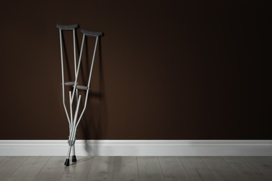Pair of axillary crutches near brown wall. Space for text