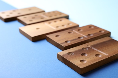 Photo of Wooden domino tiles on color background, closeup