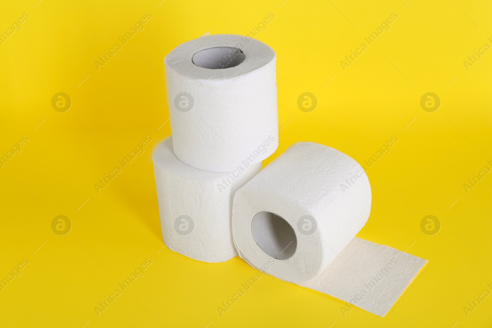 Photo of Many soft toilet paper rolls on yellow background