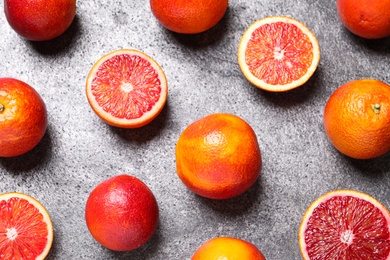 Whole and cut red oranges on grey table, flat lay