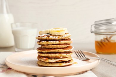 Photo of Plate of banana pancakes with honey and powdered sugar served on table