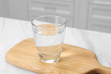 Filtered water in glass on white table indoors, closeup