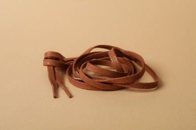Photo of Brown shoe laces on beige background. Stylish accessory