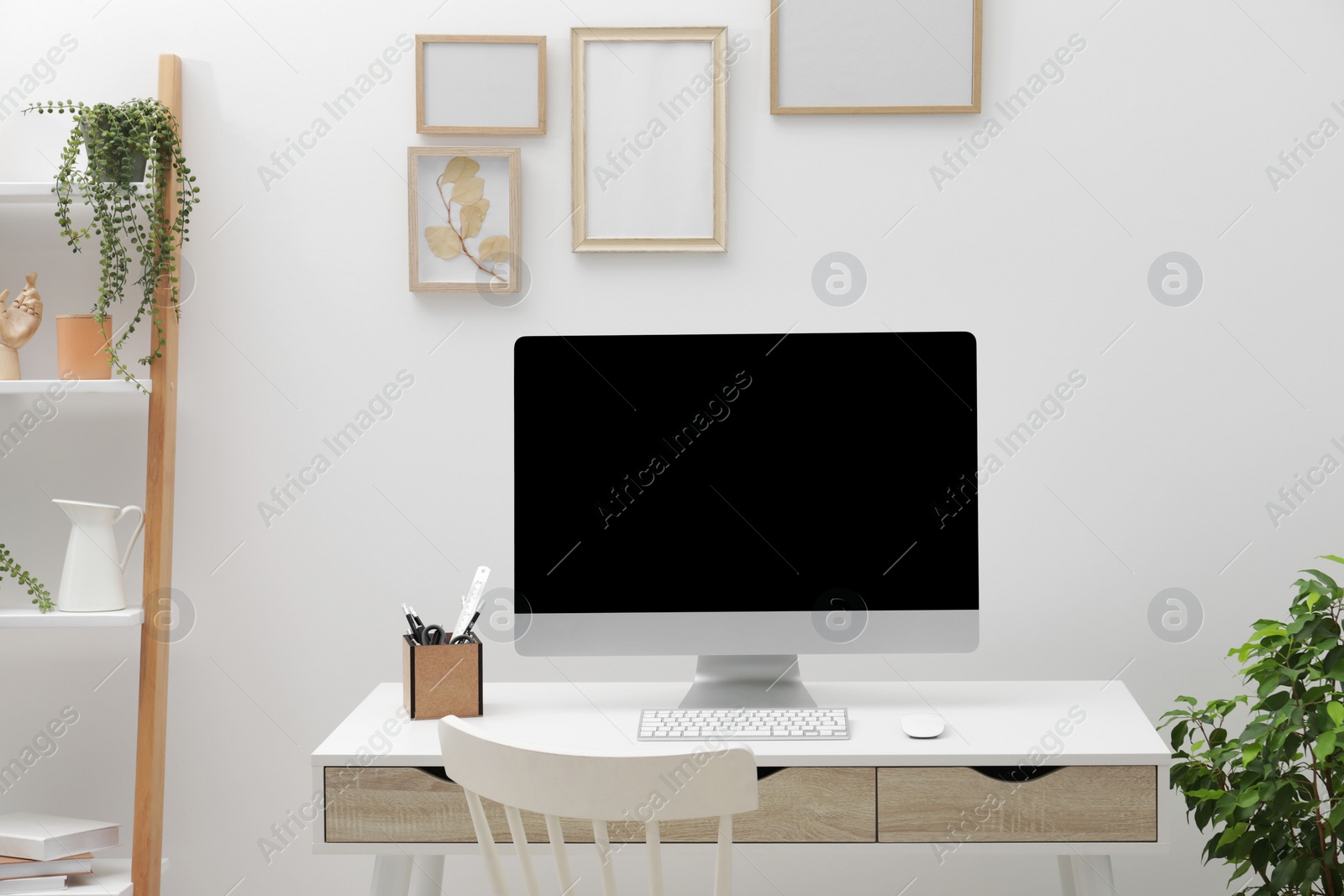 Photo of Cosy workspace with desk, chair, computer and plants at home