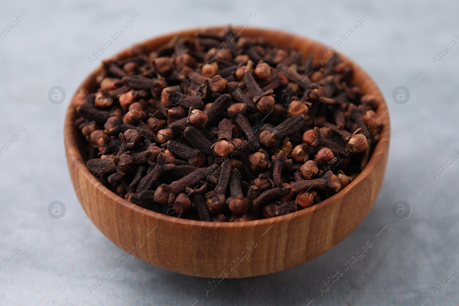 Photo of Aromatic cloves in bowl on gray table, closeup