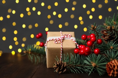 Christmas gift box with fir tree branches on wooden table