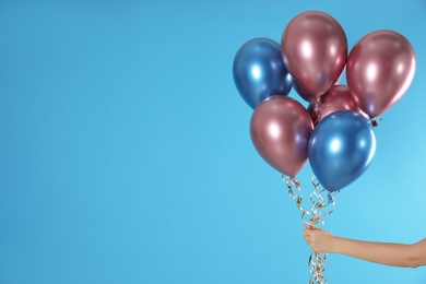 Woman holding bunch of balloons on color background, closeup. Space for text