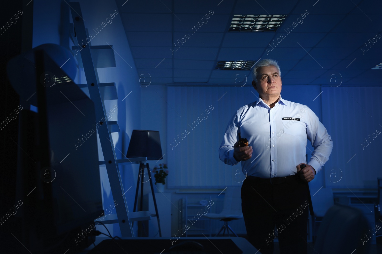 Photo of Professional security guard with portable radio set in dark office