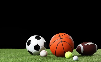 Many different sports balls on green grass against black background, space for text