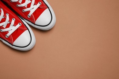 Photo of Pair of new stylish red sneakers on beige background, flat lay. Space for text