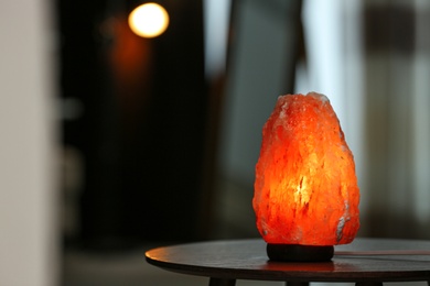 Photo of Himalayan salt lamp on table in room. Space for text