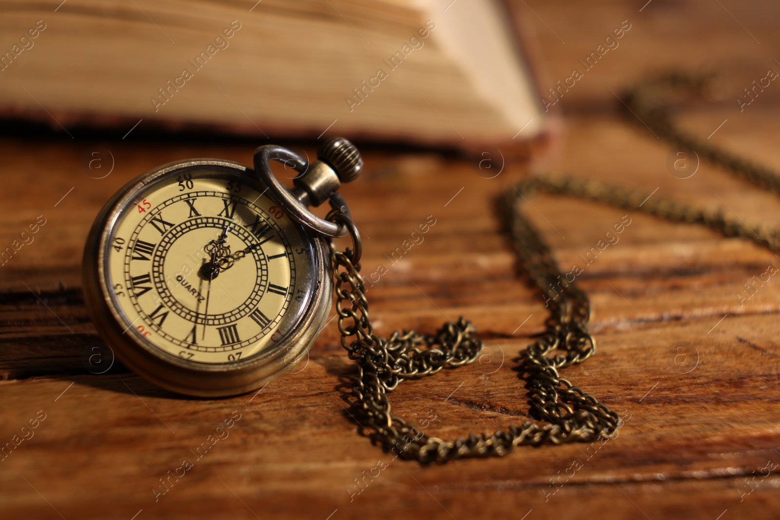 Photo of Pocket clock with chain on wooden table, closeup. Space for text