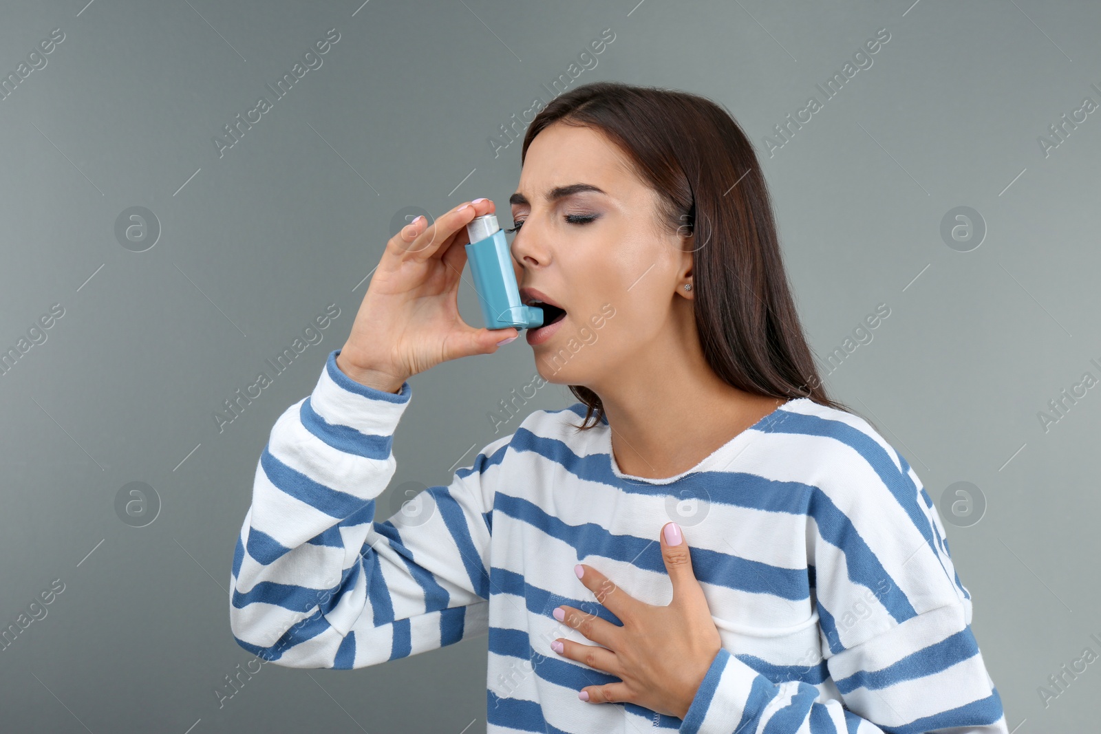 Photo of Young woman using asthma inhaler on color background