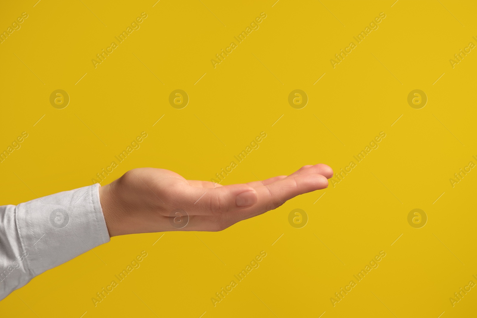 Photo of Woman holding something in hand on yellow background, closeup. Space for text