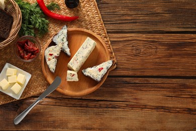 Photo of Tasty butter, dill, chili peppers and rye bread on wooden table, top view. Space for text