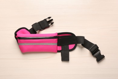 Photo of Stylish pink waist bag on white wooden table, top view