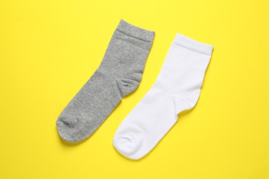 Photo of White and grey socks on yellow background, flat lay