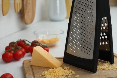 Photo of Grater, cheese and cherry tomatoes on kitchen counter, closeup