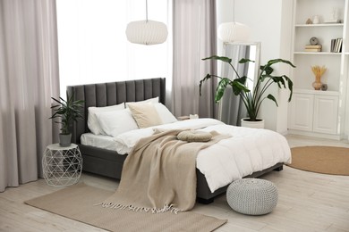 Photo of Soft beige plaid on bed in stylish bedroom. Interior design