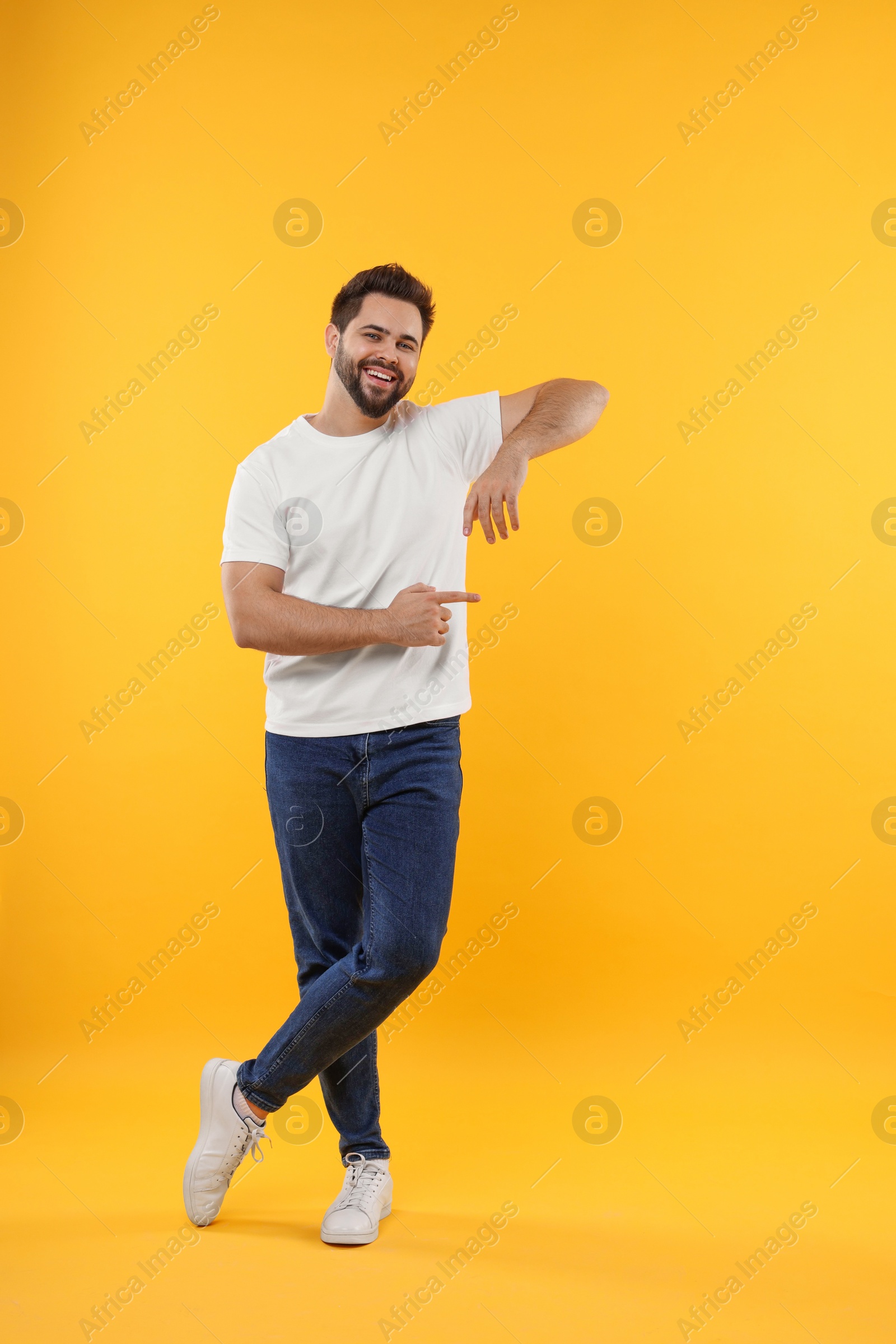 Photo of Happy young man pointing at something on yellow background