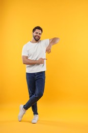 Photo of Happy young man pointing at something on yellow background