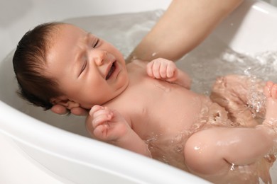 Mother bathing her cute little baby in bathtub