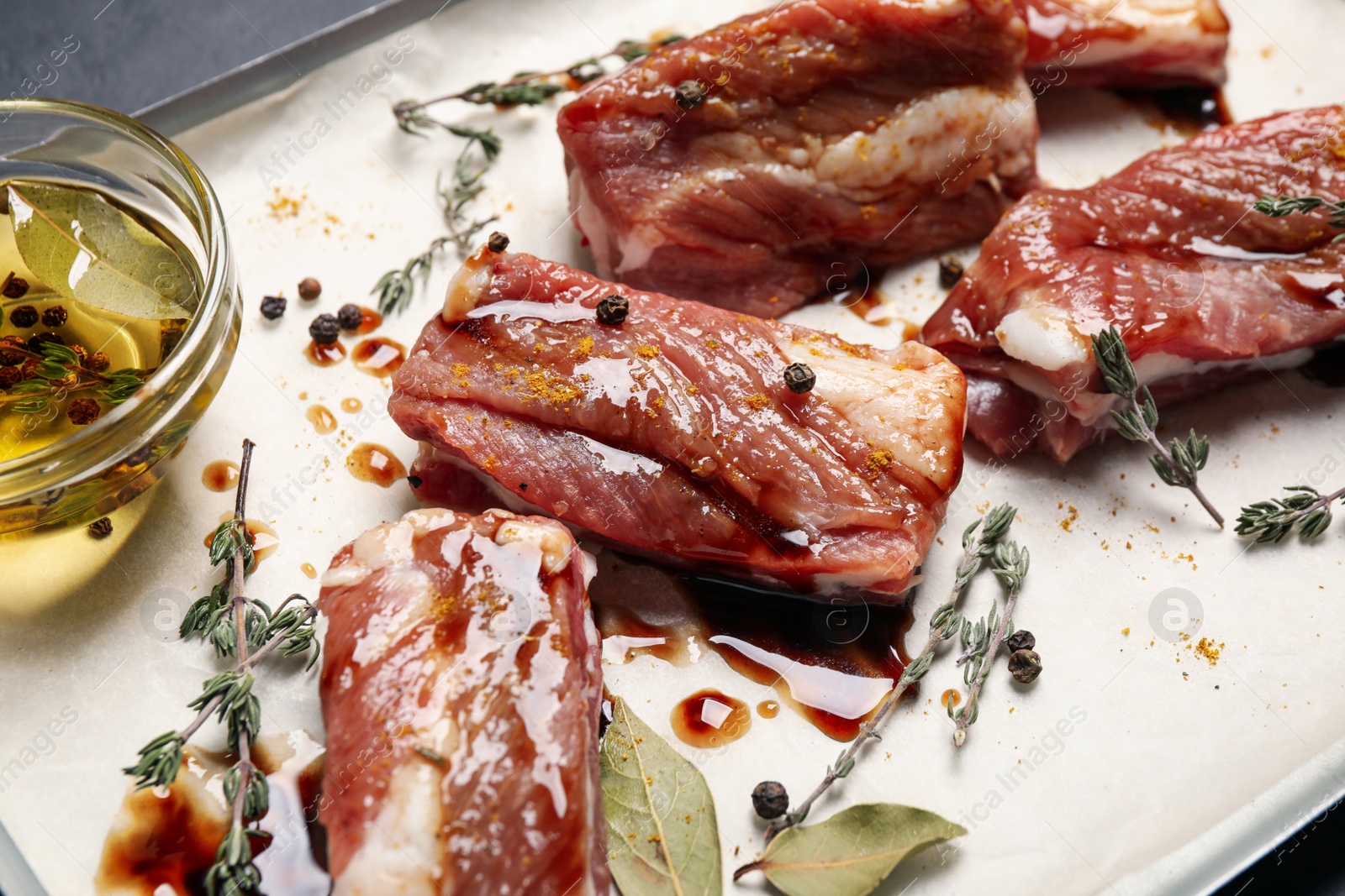 Photo of Raw marinated ribs with thyme and peppercorn, closeup