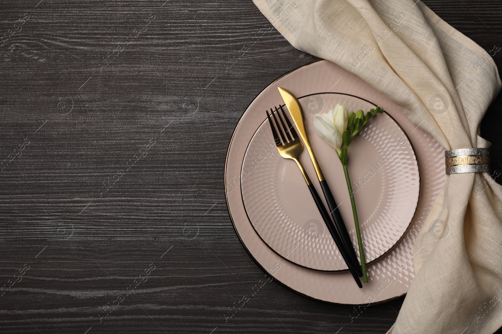 Photo of Stylish table setting. Plates, cutlery, napkin and floral decor on dark wooden background, top view with space for text