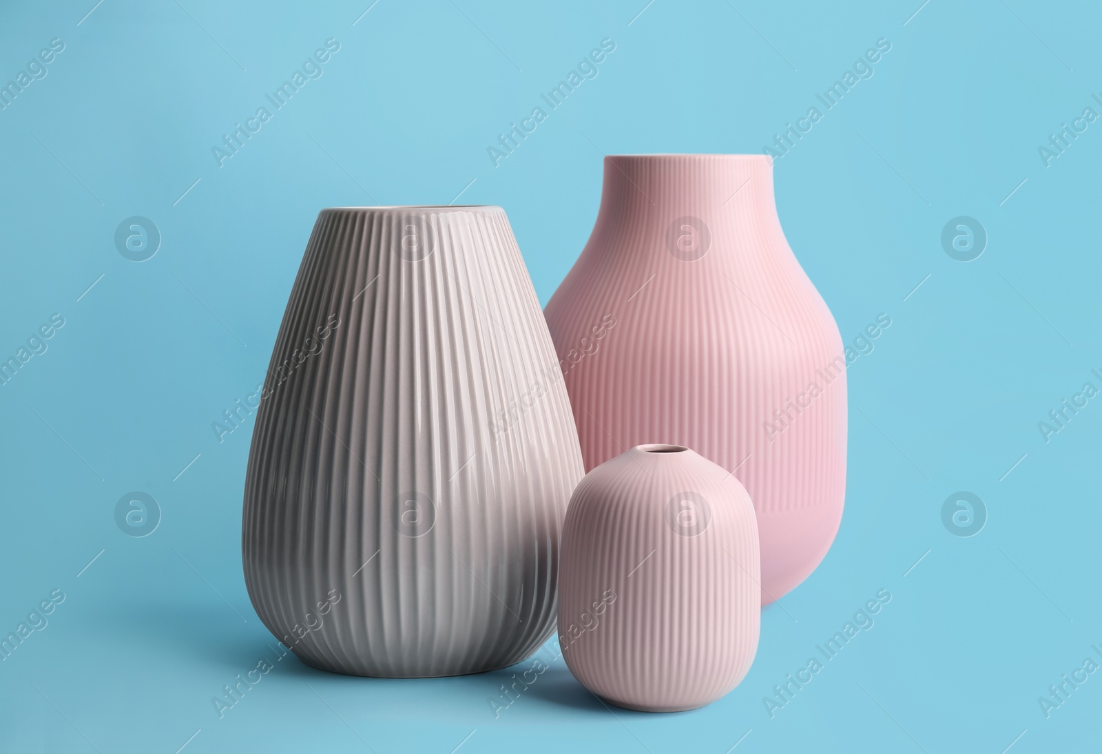 Photo of Stylish empty ceramic vases on light blue background