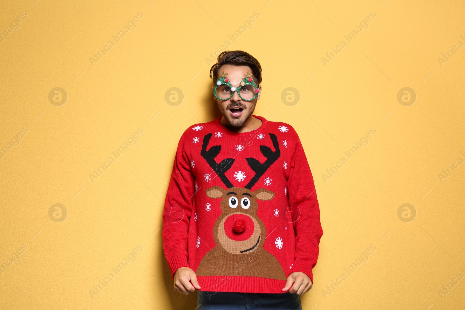 Photo of Young man in Christmas sweater with party glasses on color background