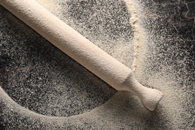 Photo of Flour and rolling pin on table, top view