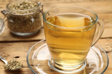 Photo of Aromatic fennel tea and seeds on wooden table, closeup