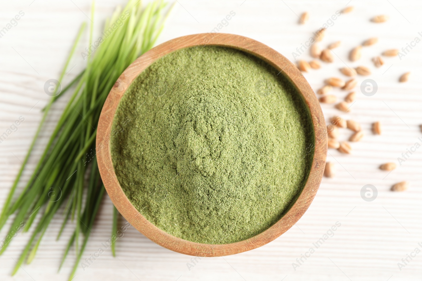 Photo of Wheat grass powder in bowl, seeds and fresh sprouts on white wooden table, flat lay