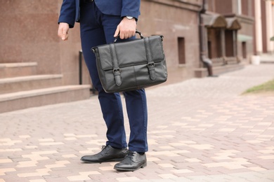 Photo of Businessman with black briefcase in hand outdoors. Space for text