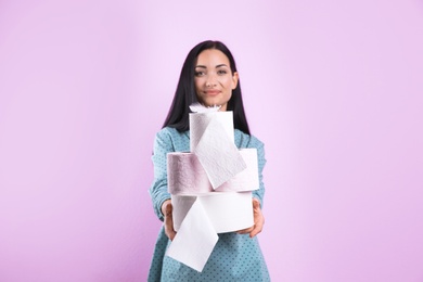 Photo of Beautiful woman holding toilet paper rolls on color background