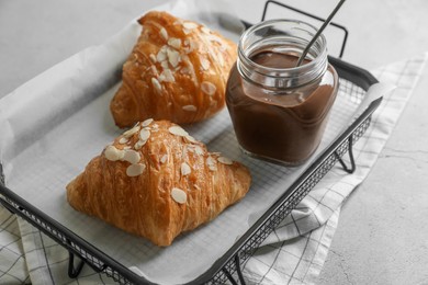 Photo of Delicious croissants with almond flakes and chocolate paste on light grey table, closeup