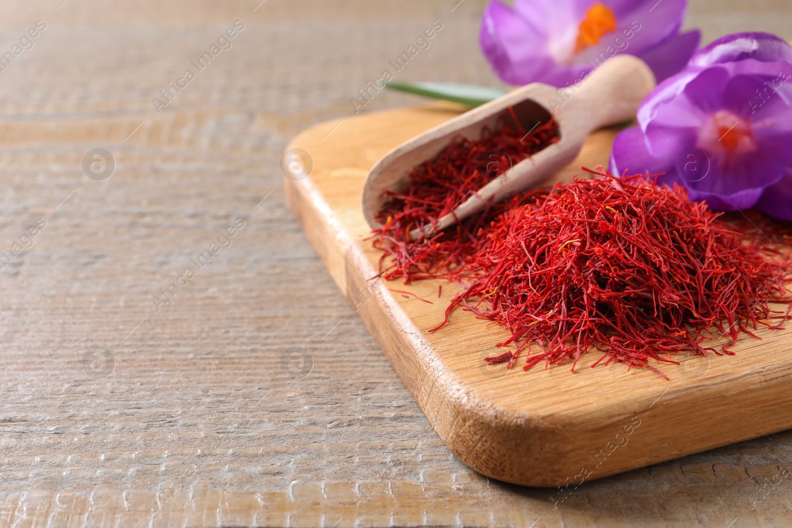 Photo of Dried saffron and crocus flowers on wooden table, closeup. Space for text