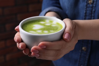 Photo of Woman with cup of delicious matcha latte, closeup