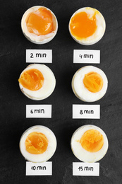Photo of Different cooking time and readiness stages of boiled chicken eggs on black table, flat lay