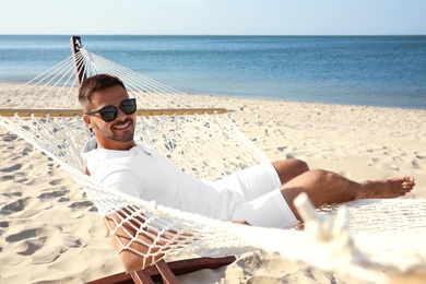 Photo of Young man relaxing in hammock on beach