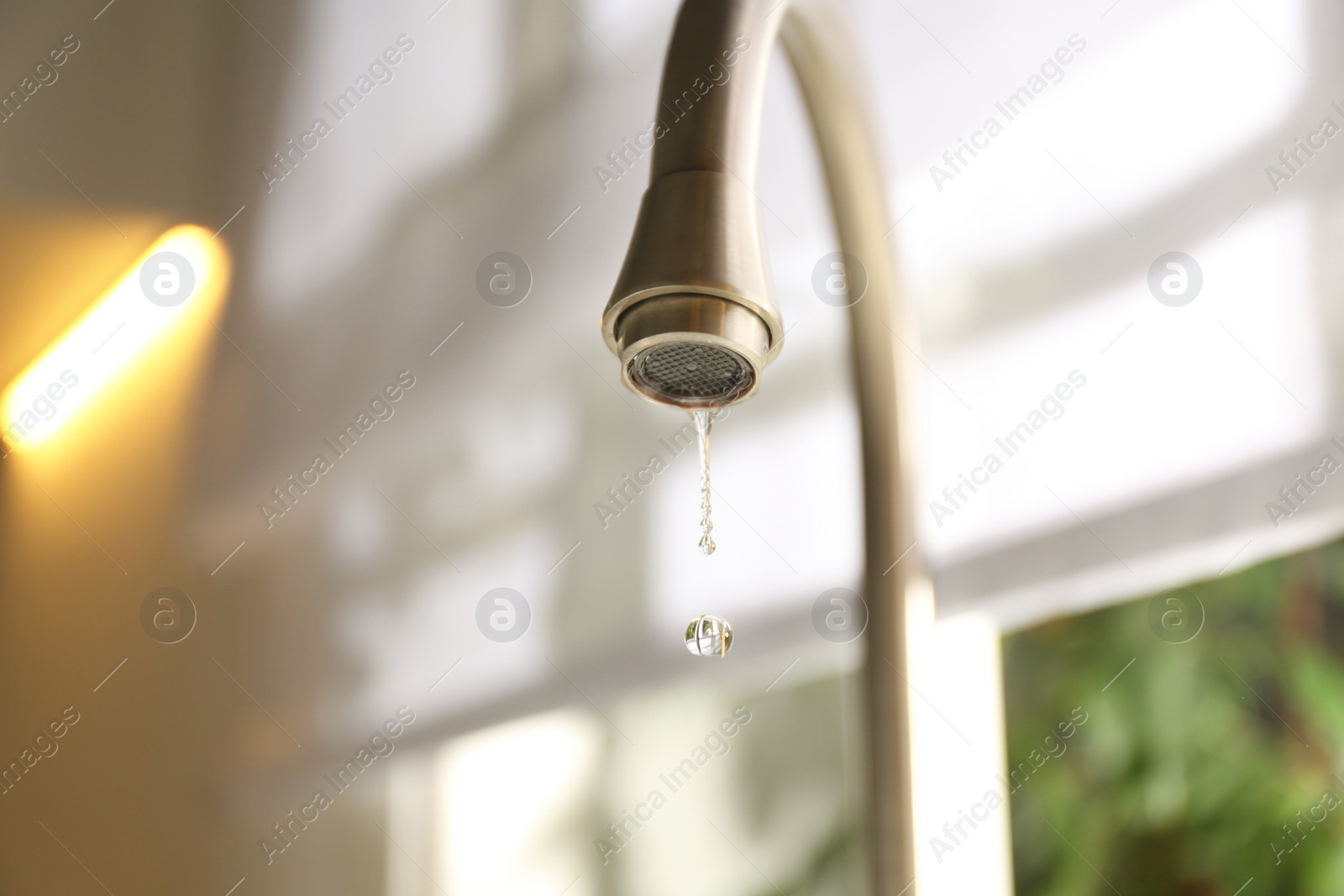 Photo of Water drops falling down from tap on blurred background, closeup