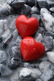 Photo of Red decorative hearts on stones and water