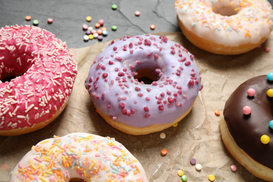 Photo of Yummy donuts with sprinkles on dark background, closeup