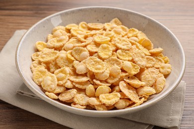 Photo of Bowl of tasty corn flakes on wooden table, closeup