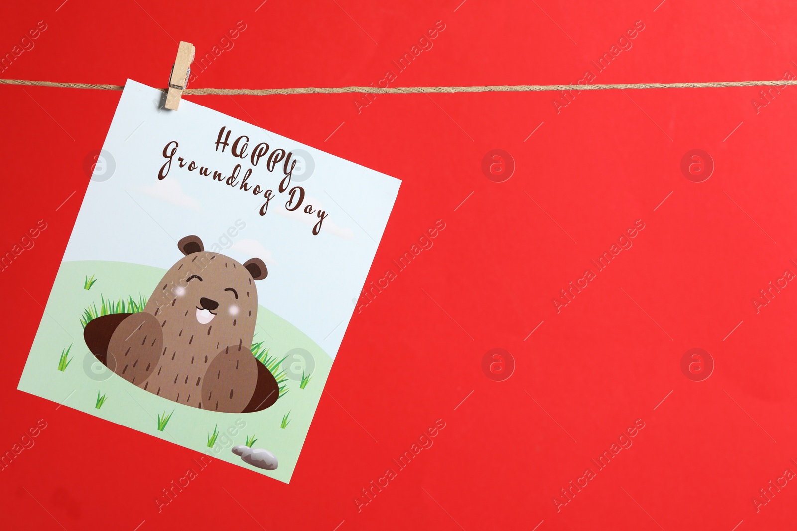 Photo of Happy Groundhog Day greeting card hanging on red background, space for text