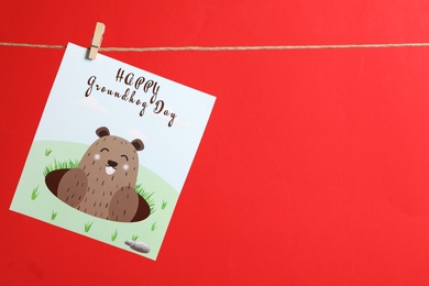 Photo of Happy Groundhog Day greeting card hanging on red background, space for text
