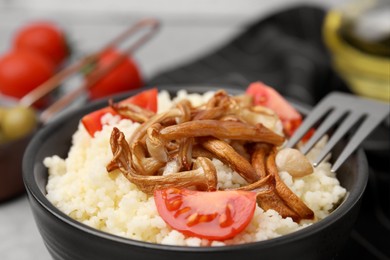 Photo of Tasty couscous with mushrooms and tomatoes on table, closeup