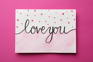 Photo of Card with phrase Love You and drawn little hearts on pink background