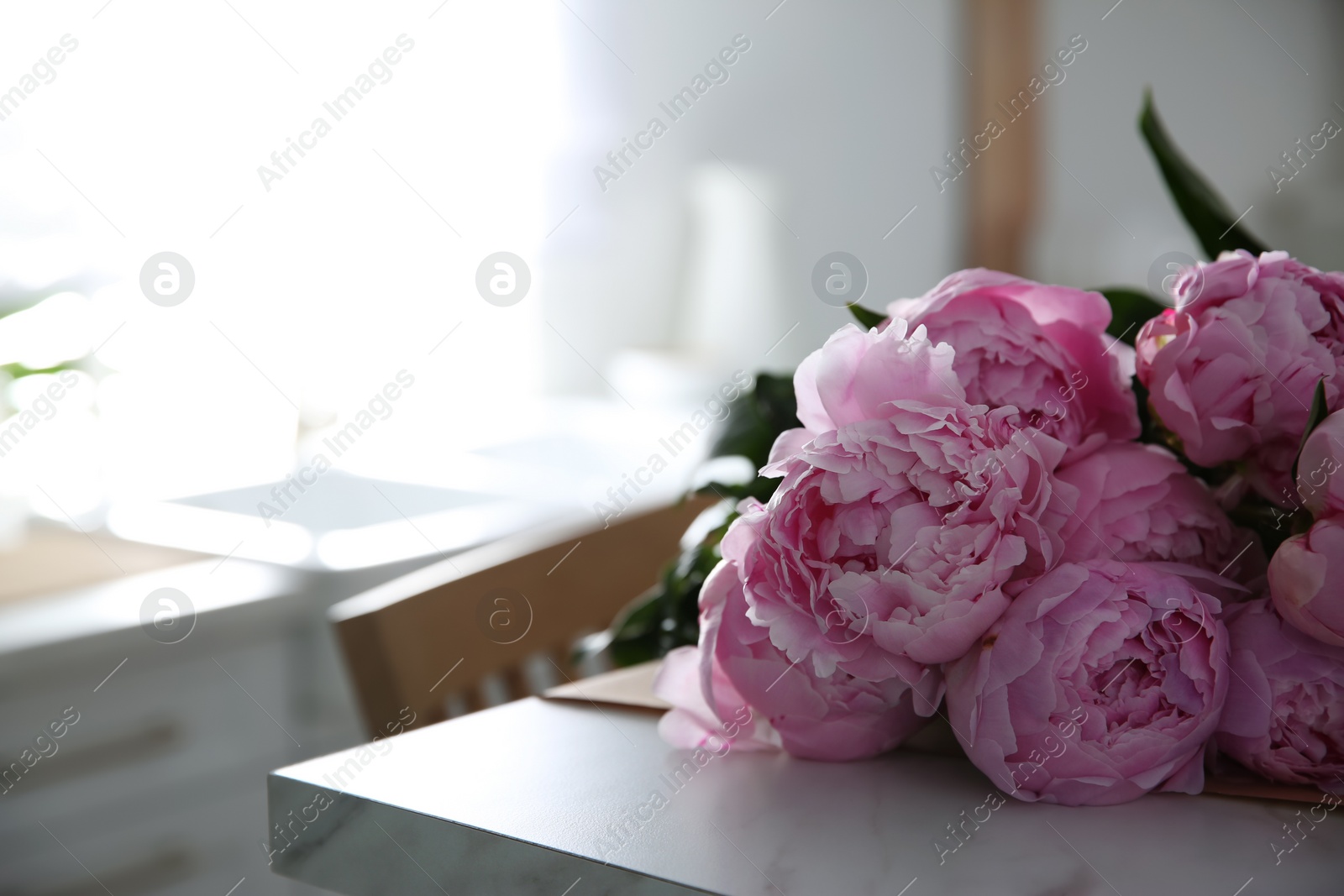 Photo of Bouquet of beautiful pink peonies on table in kitchen, closeup. Space for text