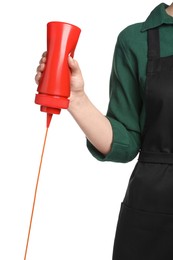 Woman pouring tasty ketchup from bottle on white background, closeup